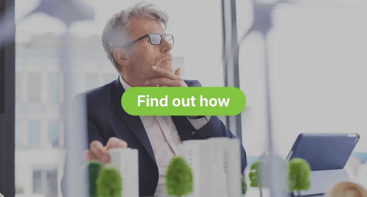 A serious, middle-aged man wearing a suit and glasses is looking off into the distance, with his hand resting on his chin in a pensive pose. He is indoors, seemingly in an office, with some blurred greenery or model buildings in the foreground. Overlaid in large white text are the words "VEU HOT WATER REBATES FOR VICTORIAN BUSINESSES" with a green call-to-action button beneath reading "Find out how".